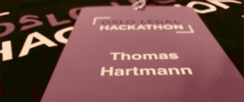 A badge that with the Oslo Legal Hackathon logo and the name Thomas Hartmann on top of a hackathon t-shirt.